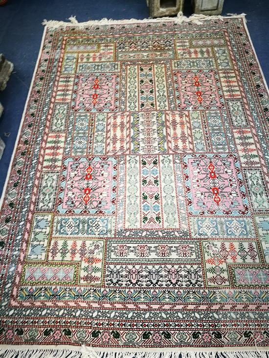 A Persian cream ground rug, woven with panels of stylised flowers 245cm x 173cm